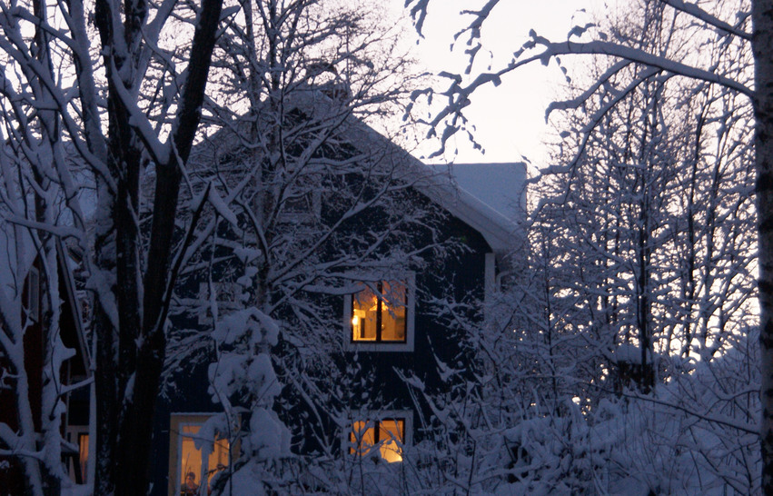 Det är tänt i fönstren i huset som ligger i skogen, allt i vinterskrud.