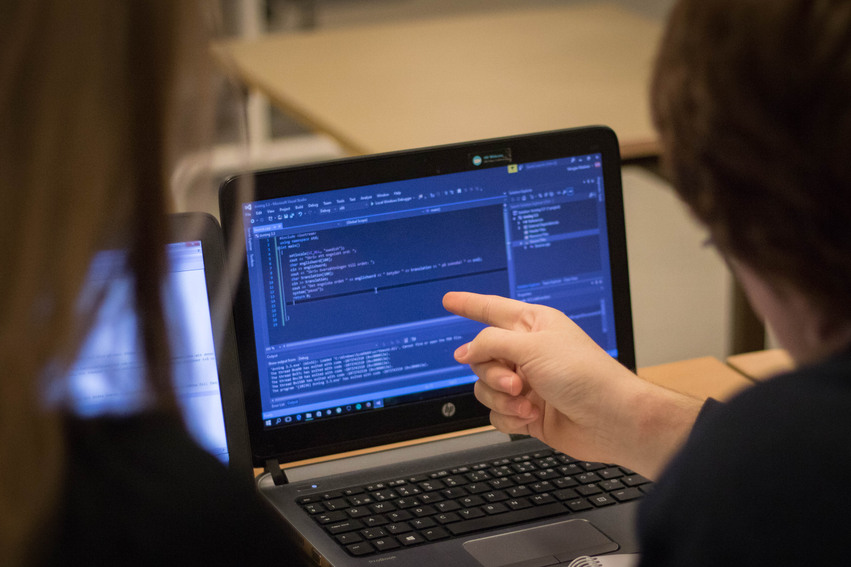 Två elever sitter framför en laptop. På skärmen syns en kod-slinga.