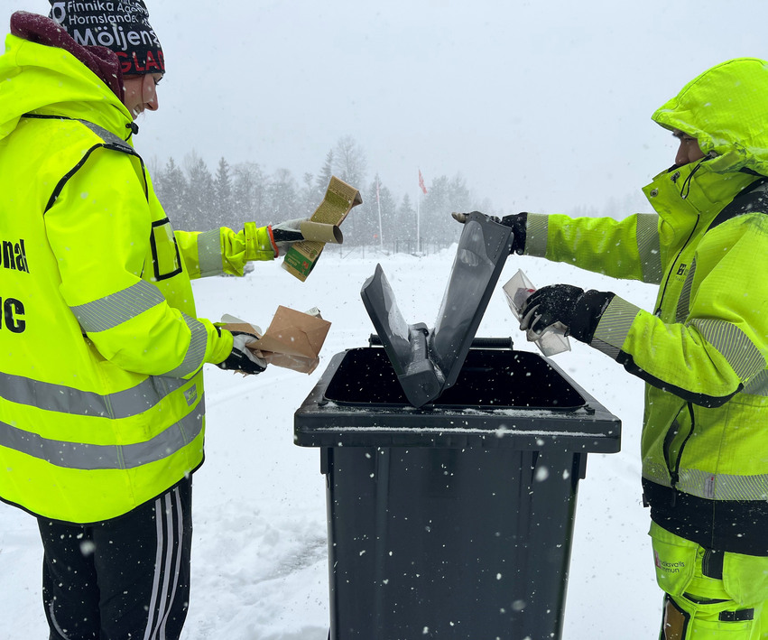 Två personer som slänger återvinning i en tunna