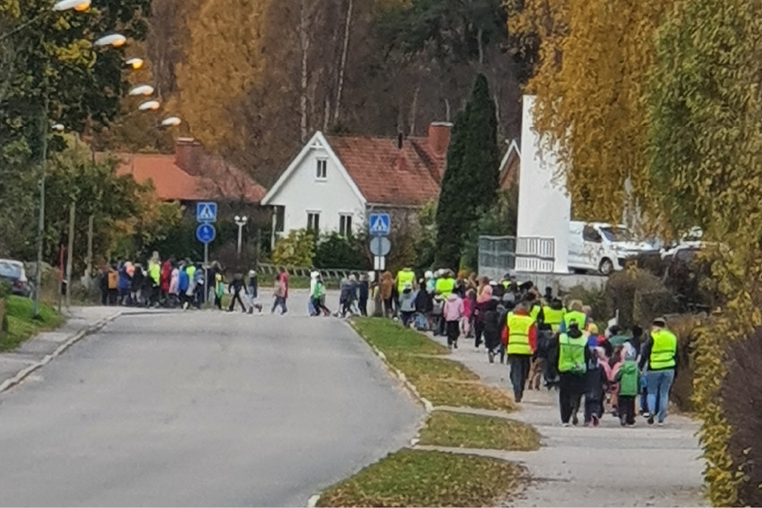 Ett 100-tal barn och personal promenerar på en gågata