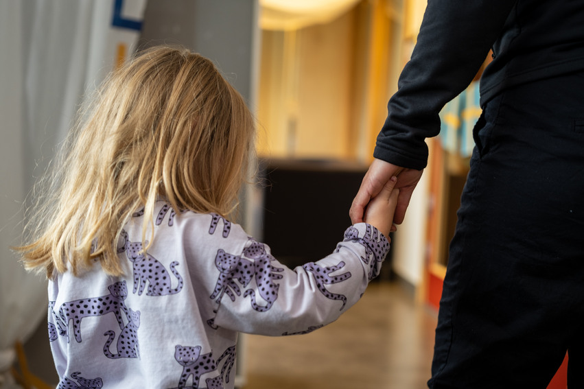 Ett barn håller hand med en förskollärare