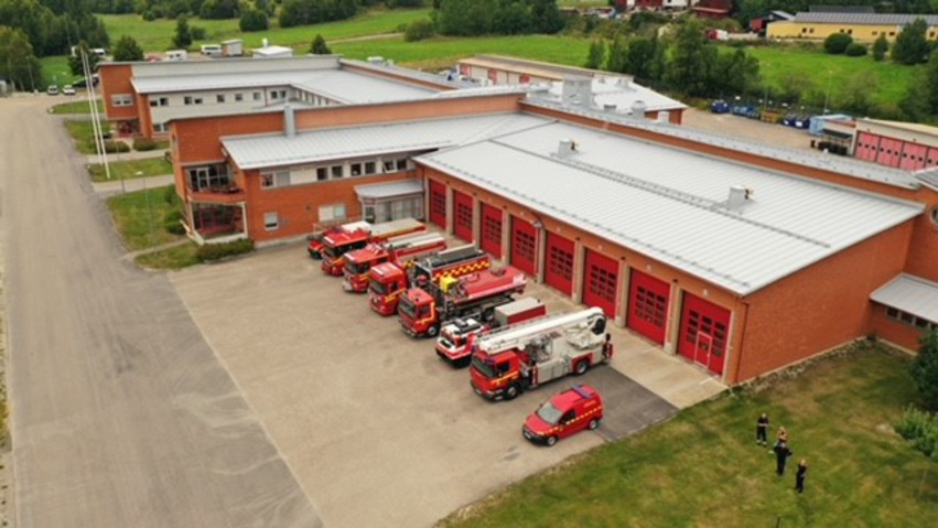 Bild på räddningstjänsten i Hudiksvalls byggnad. Framför garaget står brandbilar uppradade.