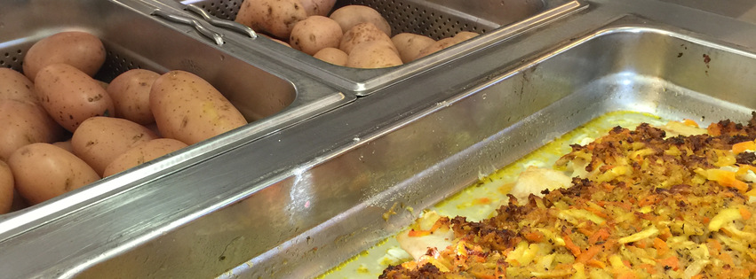 Närbild tagen på fisk och potatis som ligger i olika kantiner dit eleverna kan gå och hämta mat själva.