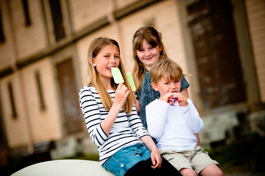 Tre barn sitter och äter glass utanför en gammal byggnad nere vid Möljen.