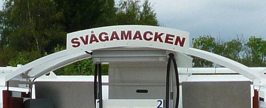 Närbild på en skylt som går i en båge i vit färg med vinröda bokstäver där det står Svågamacken med versaler.