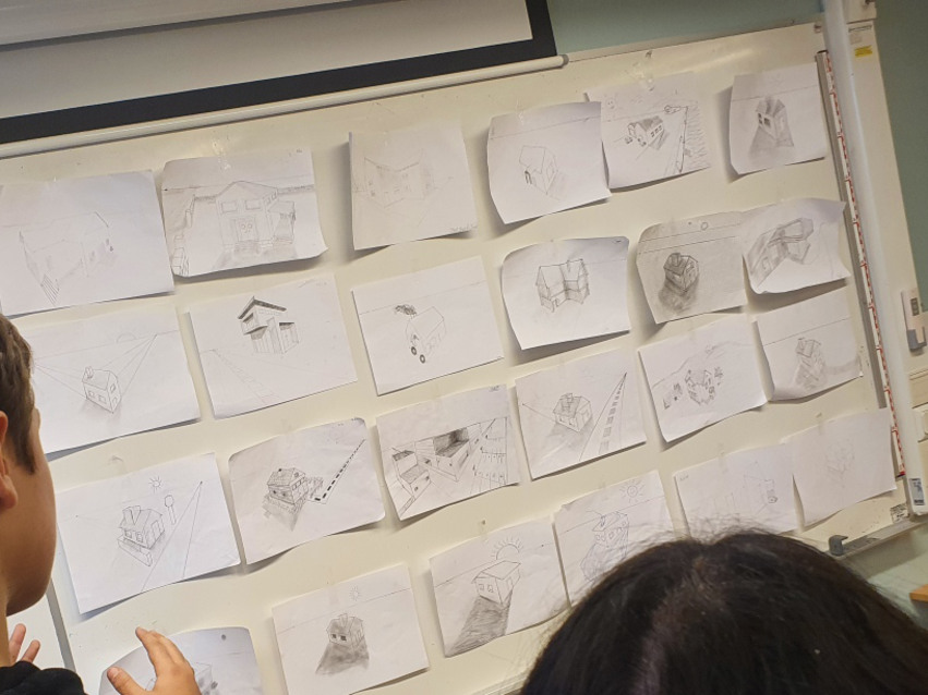 Elever sätter upp sina skisser på en vägg.