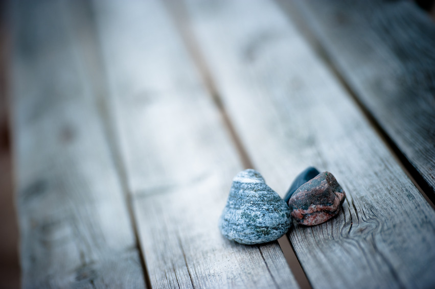 Närbild på två små stenar som ligger på en träbrygga med gråa brädor.