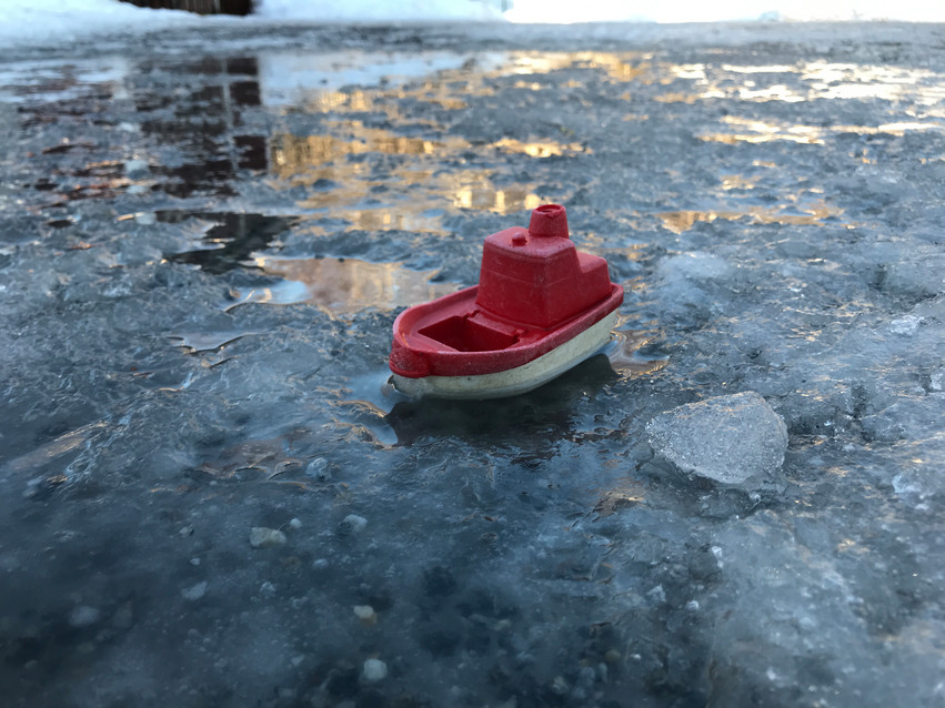 Leksaksbåt i vattenpöl med is