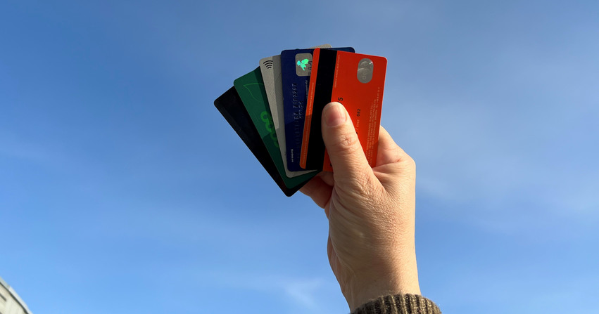 Hand som håller upp kreditkort mot en blå himmel
