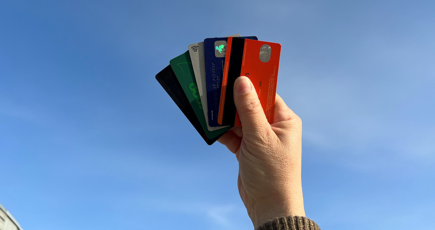 Person som håller upp kreditkort framför en blå himmel