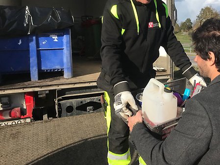 Person lämnar en låda med farligt avfall till en personal som står i miljöbilen
