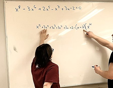 Två personer står framför en whiteboardtavla med ekvationer.