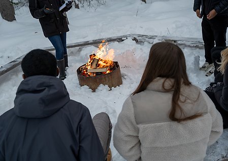 Elever runt en eld i vintermiljö.